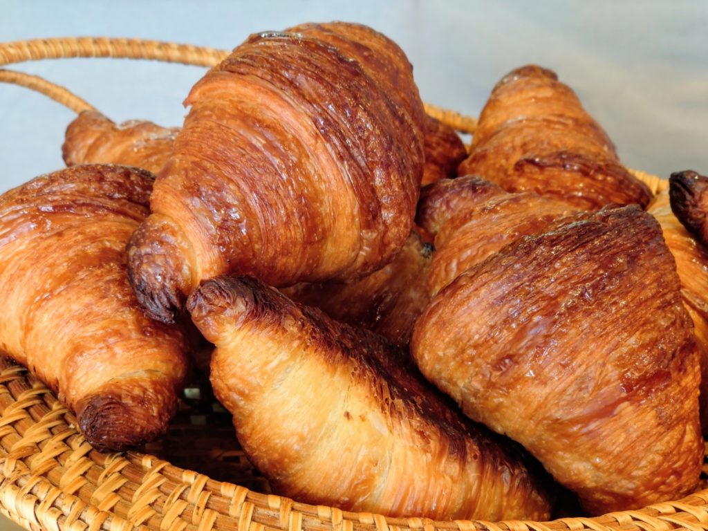 バスケットに盛られた、黄金色に輝くクロワッサン。何層にも重なった生地が美しい]